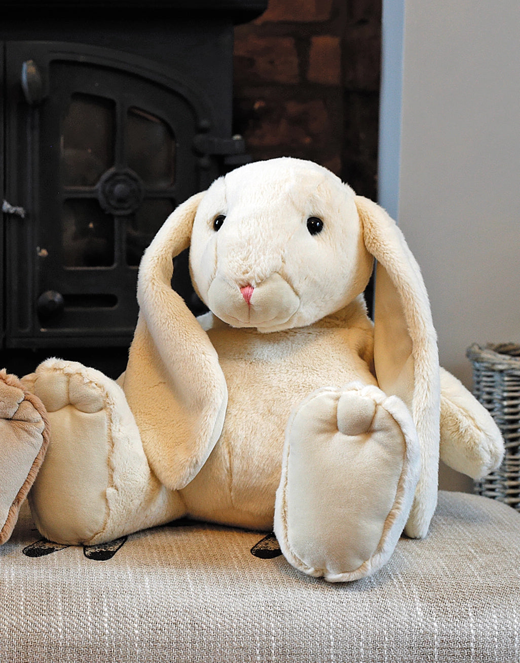 Plush rabbit toy on a textured surface with a fireplace in the background
