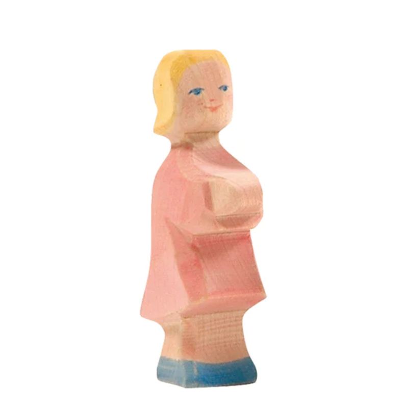 Wooden figurine of a person wearing a pink dress on a white background