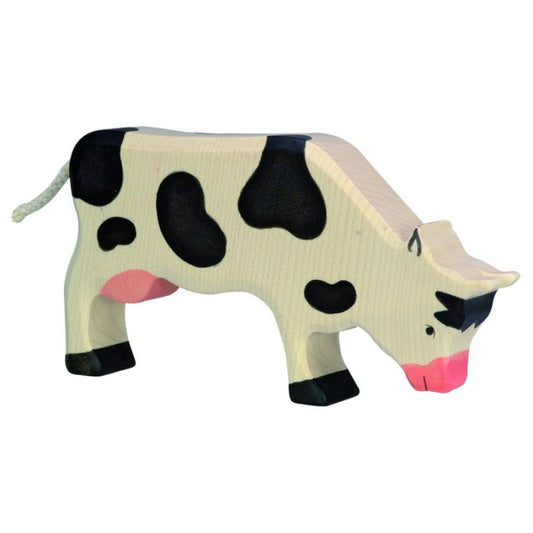 Wooden cow toy with black spots on a white background