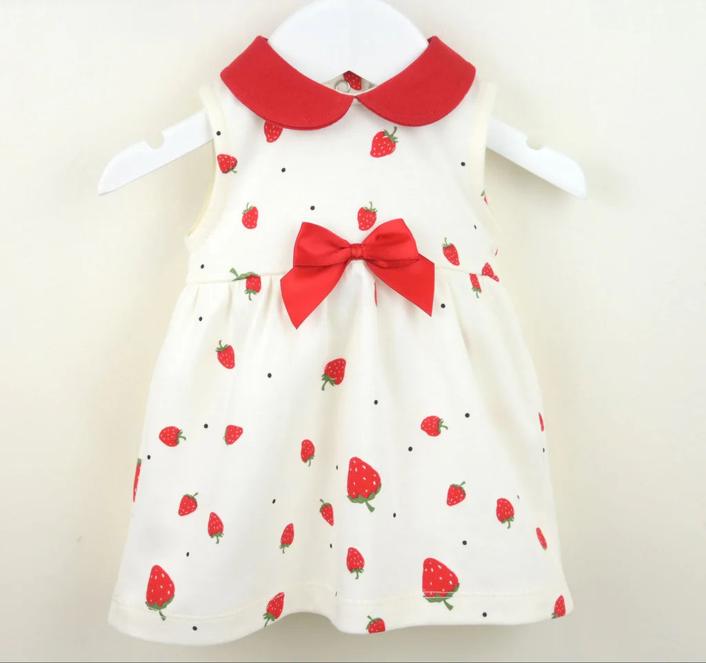White dress with red strawberry pattern and bow tie on a white background