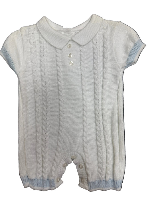 A white cable-knit baby romper with short sleeves, a Peter Pan collar, and three front buttons, laid flat on a dark textured background.
