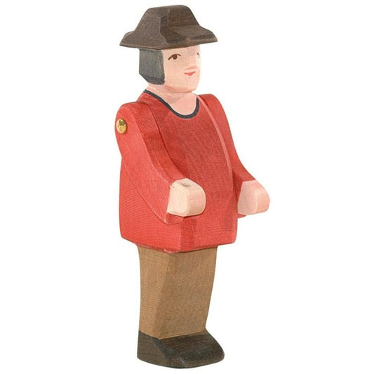 Wooden figurine of a person wearing a red jacket and brown hat on a white background